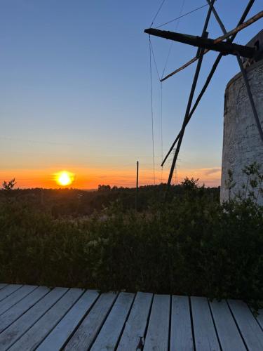 a sunset over a wooden deck with a windmill at Moinhos do Paneiro in Santiago do Cacém