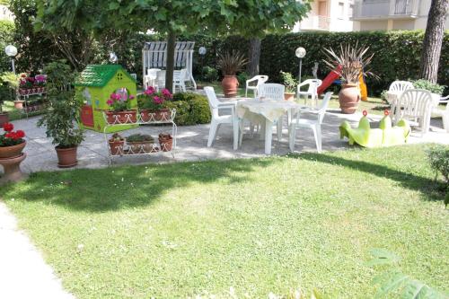 a garden with white chairs and a table and a house at Hotel Perla Del Mare in Lido di Camaiore