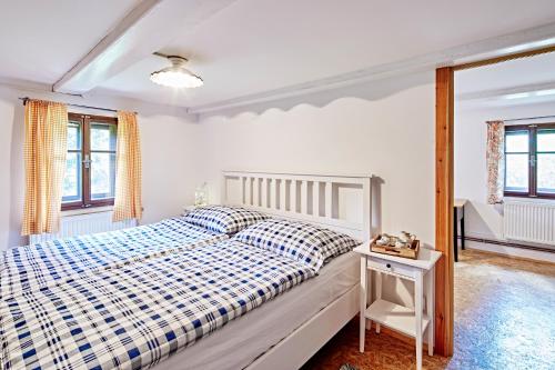 Schlafzimmer mit einem Bett mit einer blauen und weißen Bettdecke in der Unterkunft Chalupa Poustevna in Dolní Poustevna