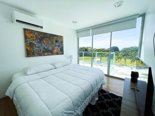 a bedroom with a white bed and a large window at Bala Bliss in Colón