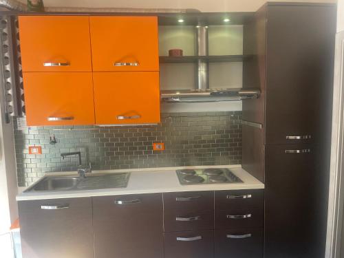 a kitchen with orange cabinets and a black refrigerator at Be Your Home - Grazioso monolocale tra porto e stazione in Civitavecchia