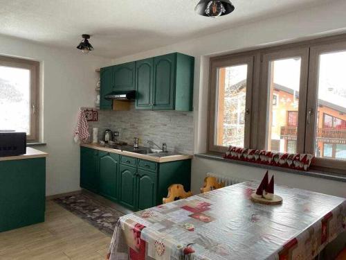 una cucina con armadi verdi e un tavolo con una tovaglia di Appartamento Gnomo Livigno a Livigno