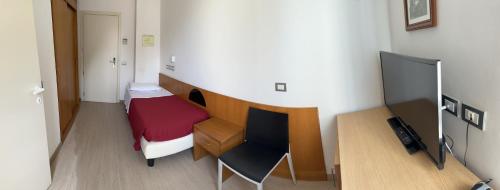 a small room with a bed and a desk at Hotel Morolli in Rimini