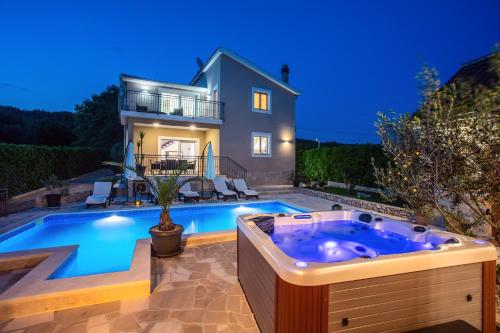 a swimming pool with a jacuzzi in front of a house at VIP Luxury villa with a heated pool and jacuzzi-Granny's Gold in Lovreć