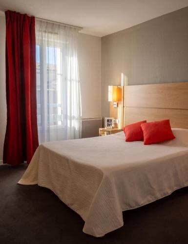 une chambre avec un grand lit blanc avec des oreillers rouges dans l'établissement Résidence services Les Essentielles Sainte Soulle, à Sainte-Soulle