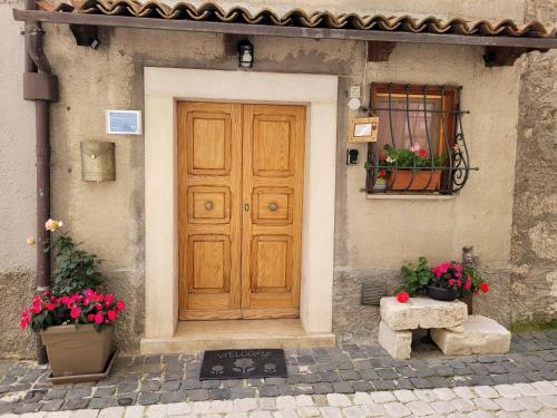 una porta di legno di una casa con due vasi di fiori di B&B Valle Cicala a Pescasseroli