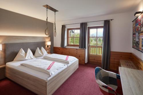 a hotel room with a bed and a table and windows at Gut Wenghof - Family Resort Werfenweng in Werfenweng