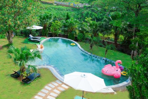 an overhead view of a swimming pool with a pink swan and an umbrella at Rose Villa in Hòa Bình