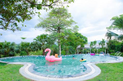 a pool with a pink flamingo and people in it at White Villa in Hòa Bình