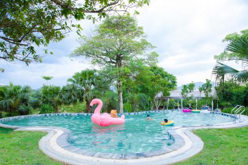 a pool with a pink flamingo and people in it at Rose Villa in Hòa Bình