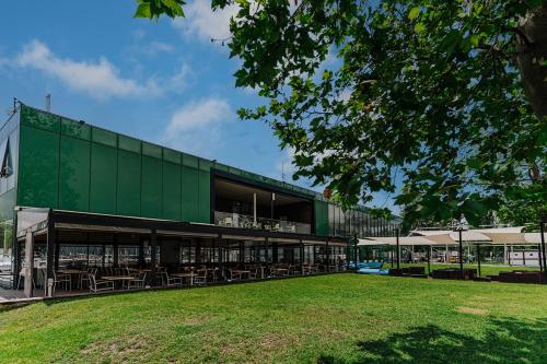 a green building with tables and chairs in a park at Butique Apartman in Balatonlelle