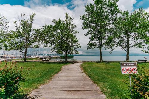 a path leading to a marina with trees and a sign at Butique Apartman in Balatonlelle