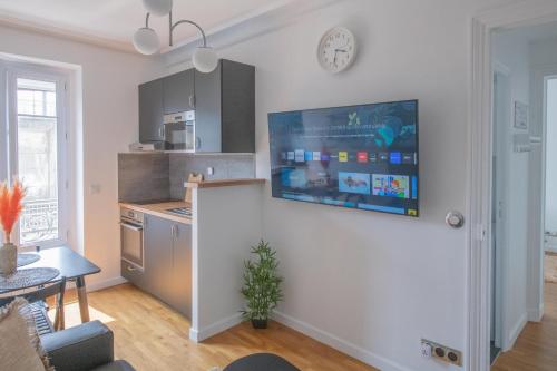 Il comprend un salon avec une cuisine et une télévision murale. dans l'établissement Paris Bercy - Charming Apartment 2 rooms, à Paris
