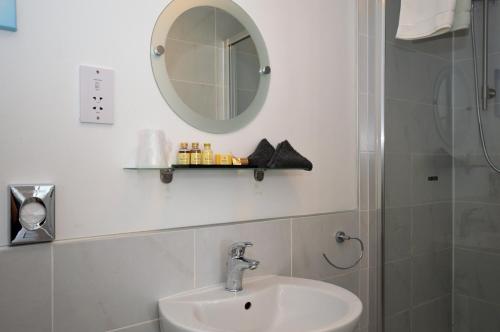 a bathroom with a sink and a mirror and a shower at Fyne Rooms in Tighnabruaich