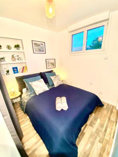 - une chambre avec un grand lit bleu et des chaussons dans l'établissement Gîte cosy entre Bordeaux et Lacanau, à Sainte-Hélène