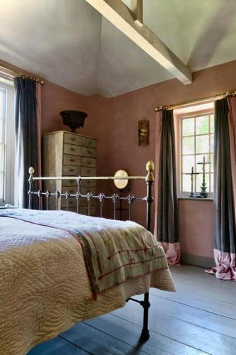 a bedroom with a bed and two windows at Monastery Cottage in Rye
