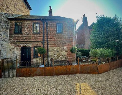 an old brick house with a fence in front of it at Monastery Cottage in Rye