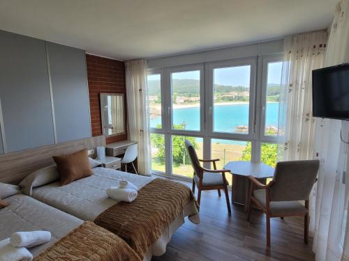 a bedroom with a large bed and a large window at Complejo turistico el Merendero in Finisterre