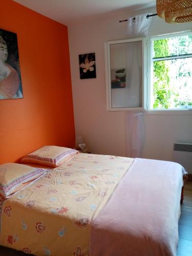 Bett in einem Zimmer mit orangefarbener Wand in der Unterkunft Le chêne blanc in La Genétouze