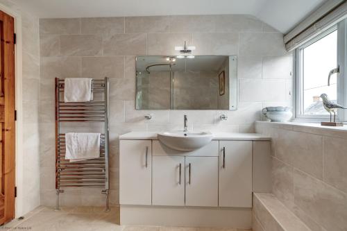 Baño blanco con lavabo y espejo en Meadow Cottage en Bicester