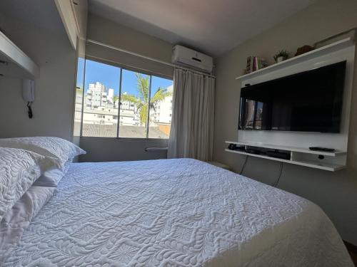 um quarto com uma cama e uma televisão de ecrã plano em Edificio Long Beach em Balneário Camboriú