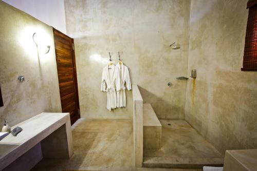 a bathroom with a robe hanging on a wall at Otjiwa Safari Lodge in Otjiwarongo
