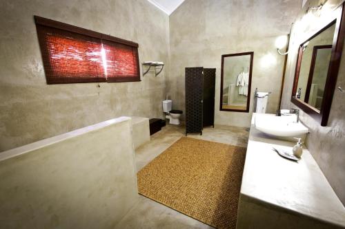 a bathroom with a sink and a tub and a toilet at Otjiwa Safari Lodge in Otjiwarongo