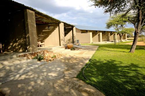 a house with a walkway in front of a yard at Otjiwa Safari Lodge in Otjiwarongo