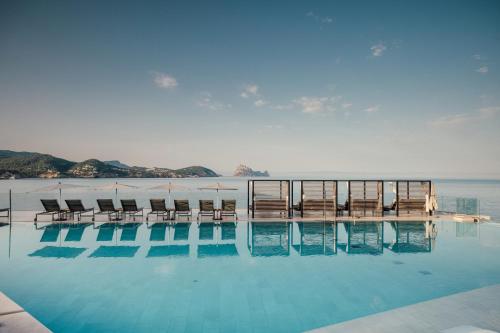 サン・ホセにある7Pines Resort Ibiza, part of Destination by Hyattの海を背景にスイミングプール(椅子付)