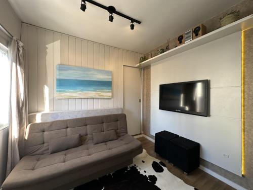 uma sala de estar com um sofá e uma televisão de ecrã plano em Edificio Long Beach em Balneário Camboriú