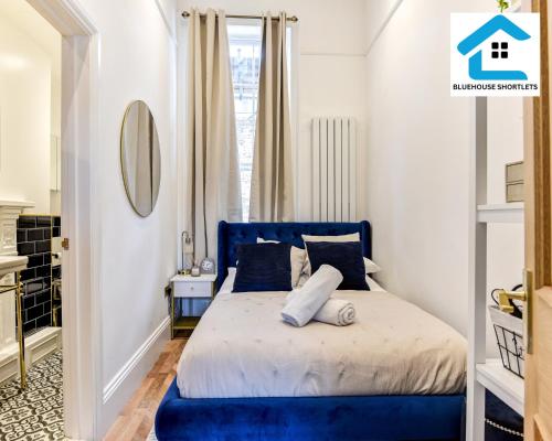 a blue bed in a room with a window at Seaside Apartment By Bluehouse Short Lets Brighton With Stunning Views Leisure Family in Brighton & Hove
