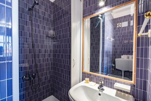 Baño de azulejos azules con lavabo y espejo en Apartamentos Pátio Victória by Umbral en Vila Nova de Milfontes