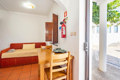 a room with a bed and a table and a desk at Apartamentos Pátio Victória by Umbral in Vila Nova de Milfontes