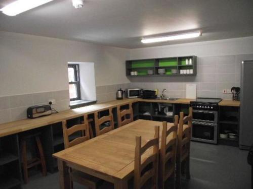 a kitchen with a wooden table and wooden chairs at Highlander Bunkhouse in Huntly