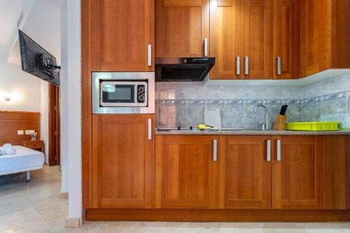 a kitchen with wooden cabinets and a microwave at CT 240 - Beachfront Apartment -Don Juan Manilva in Manilva