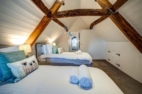 2 Betten in einem Dachzimmer mit Holzbalken in der Unterkunft Greenhill Farmhouse in Bletchingdon
