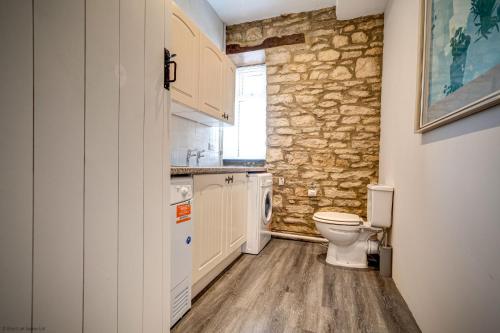 a bathroom with a toilet and a stone wall at Greenhill Farmhouse in Bletchingdon