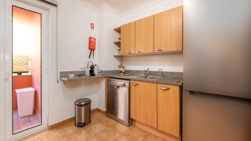 a kitchen with wooden cabinets and a stainless steel refrigerator at Jardim da Meia Praia Resort in Lagos