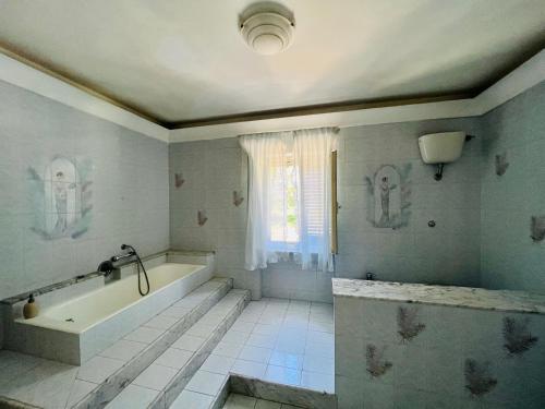 baño blanco con bañera y ventana en Be Your Home - Villa Rosi, en Civitavecchia