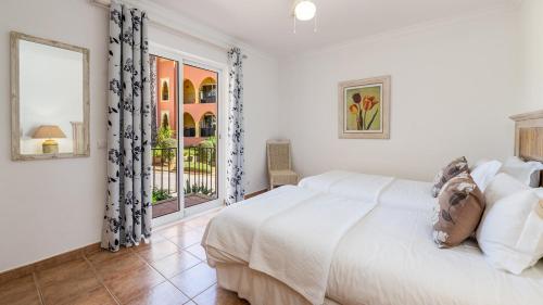 a bedroom with a large white bed and a window at Jardim da Meia Praia Resort in Lagos