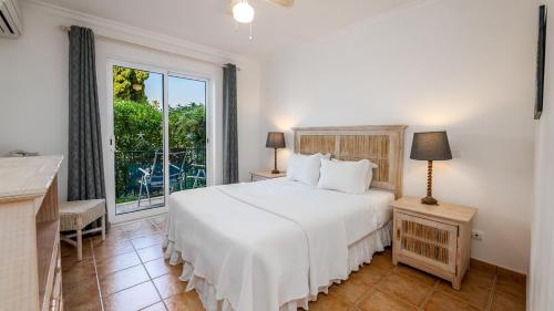 a bedroom with a white bed and a window at Jardim da Meia Praia Resort in Lagos