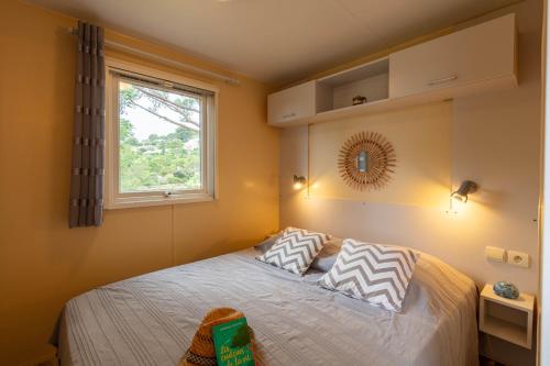 - une chambre avec un lit avec deux oreillers et une fenêtre dans l'établissement L Arbousier, mobil-home vue dégagée sur la mer, à Hyères