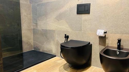 a bathroom with a black toilet and a sink at Palazzo Gatto Bianco in Bari