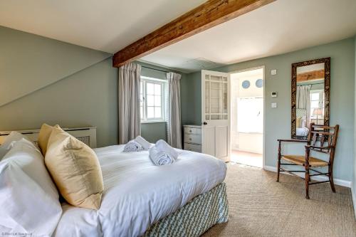 Un dormitorio con una gran cama blanca y una silla. en Church End Cottage, en Swerford