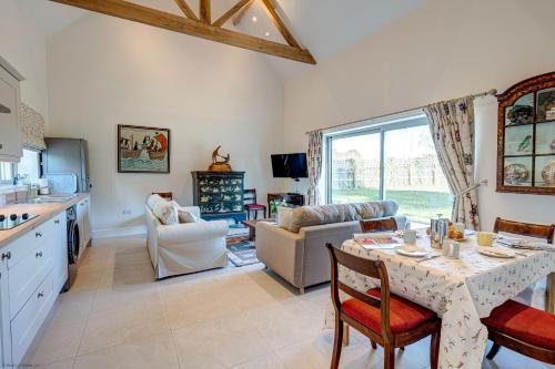 a kitchen and living room with a table and a kitchen and a dining room at Dairy Lodge in Bladon