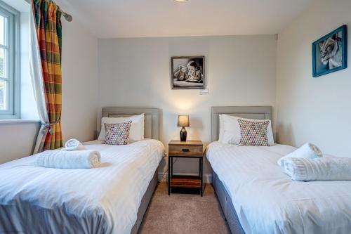 two twin beds in a room with a night stand at Dairy Lodge in Bladon