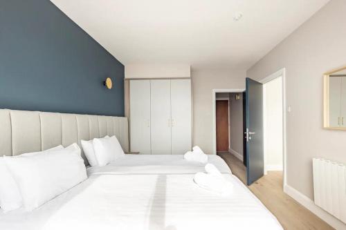 a bedroom with two white beds and a blue wall at Galway Bay Sea View Apartments in Galway