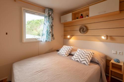 a small bedroom with a bed and a window at Le Photinia, mobil-home climatisé avec vue mer situé au cœur du domaine in Hyères