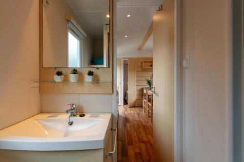 une salle de bain avec un lavabo et un miroir dans l'établissement Le Photinia, mobil-home climatisé avec vue mer situé au cœur du domaine, à Hyères