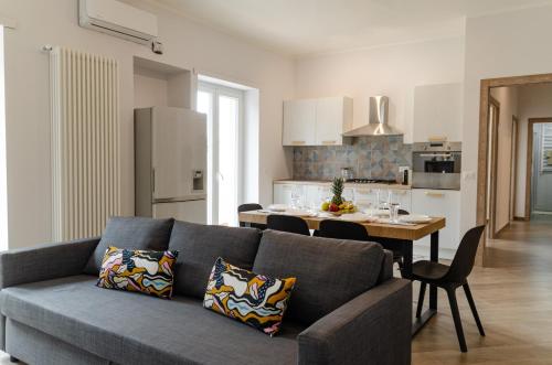 a living room with a blue couch and a kitchen at Don Gaetano Apartment - Nel Cuore di Napoli in Naples